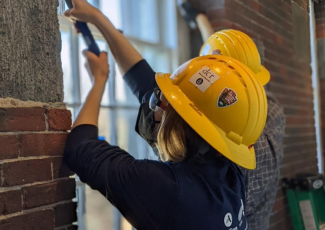 SCA crew member in yellow hard helmet restoring window