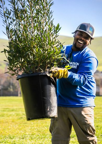 SCA crew member smiling while holding a plant in a bucket