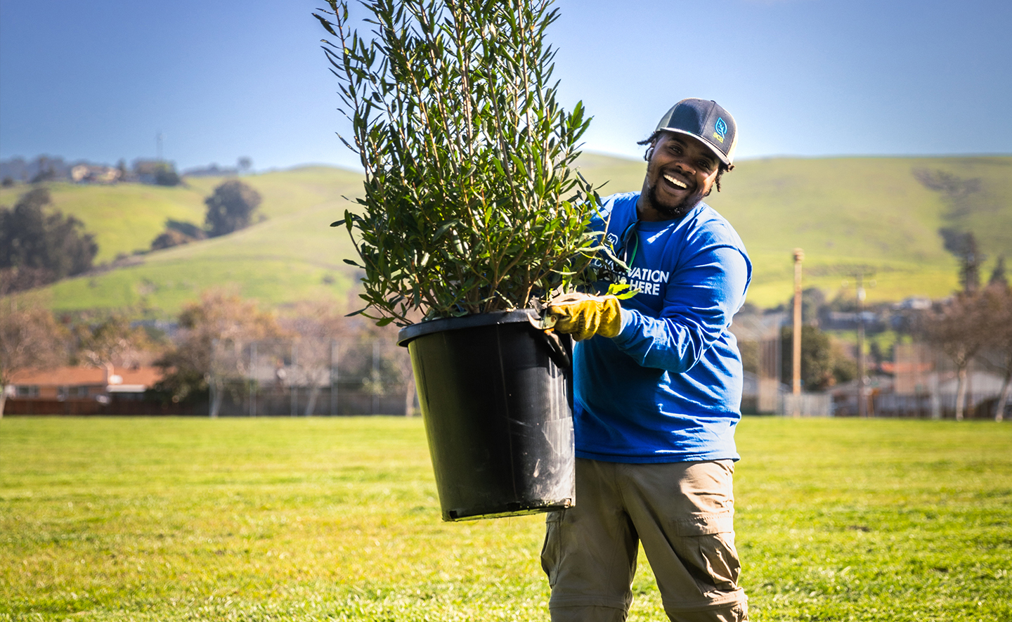 SCA crew member smiling while holding a plant in a bucket