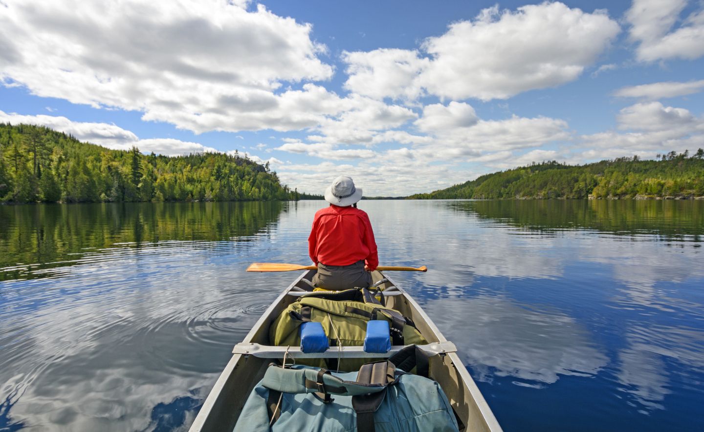 Person earing a red shirt in a canoe on Kekekabic Lake in the Boundary Waters in Minnesota